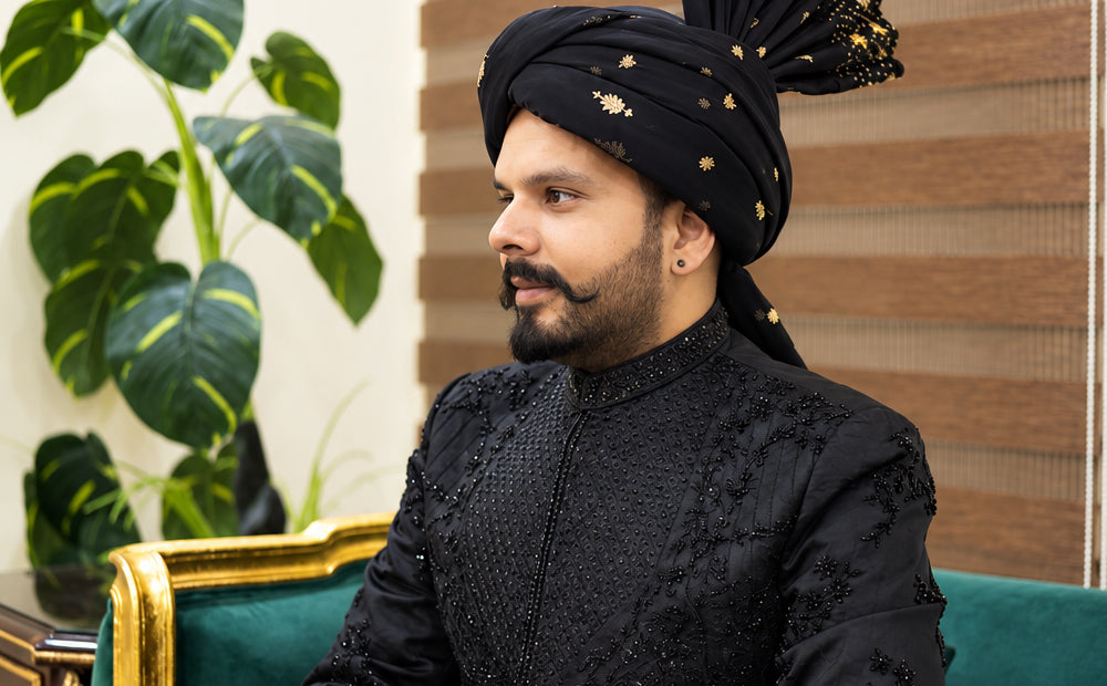 1.	Close-up of a black velvet sherwani showing hand work on the high collar and hand-stitched buttons down the front placket